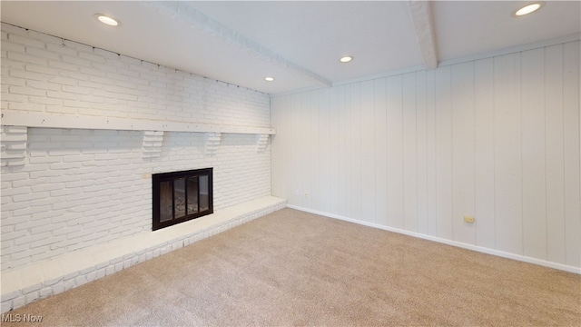 unfurnished living room featuring brick wall, carpet floors, a fireplace, and beam ceiling