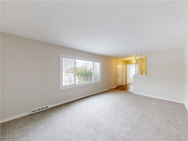 unfurnished room with a textured ceiling and carpet flooring