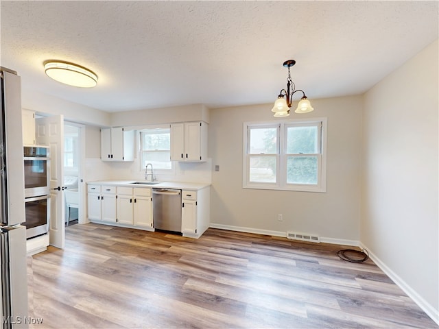 kitchen featuring pendant lighting, white cabinets, sink, and dishwasher