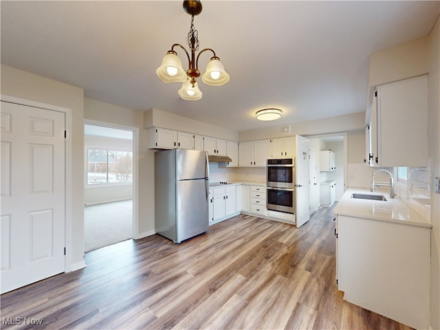 kitchen featuring white cabinetry, wood-type flooring, sink, hanging light fixtures, and stainless steel appliances