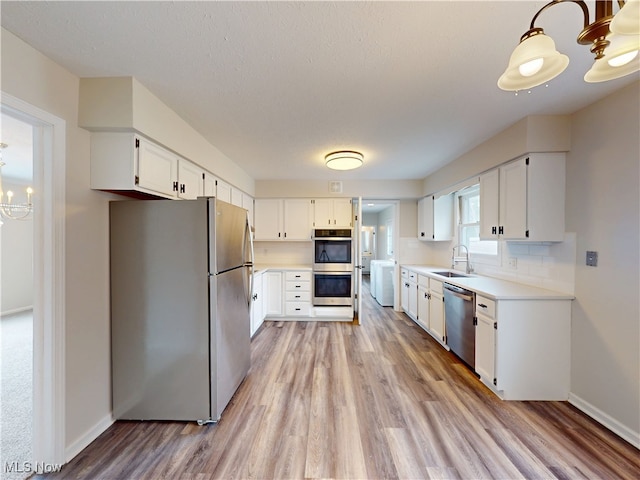 kitchen with appliances with stainless steel finishes, a chandelier, light hardwood / wood-style floors, and white cabinets