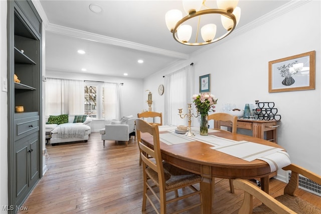 dining area with an inviting chandelier, wood-type flooring, and ornamental molding