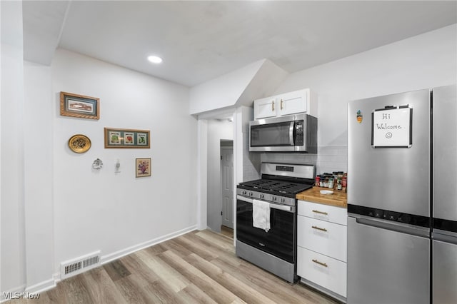 kitchen featuring white cabinetry, tasteful backsplash, light hardwood / wood-style floors, and appliances with stainless steel finishes