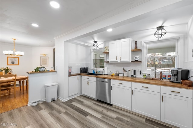 kitchen with wood counters, sink, white cabinetry, hanging light fixtures, and dishwasher