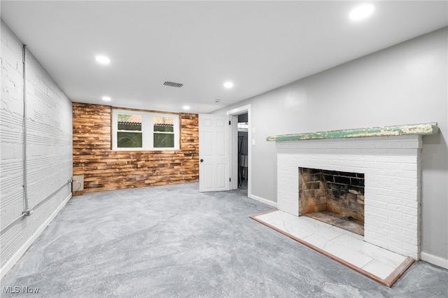 unfurnished living room featuring wooden walls, a tiled fireplace, and carpet floors