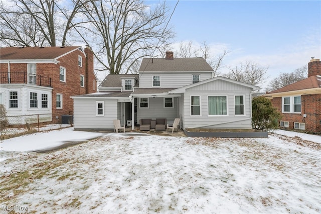 snow covered rear of property featuring central AC