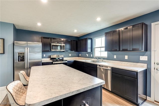 kitchen with a kitchen island, appliances with stainless steel finishes, sink, and light hardwood / wood-style floors