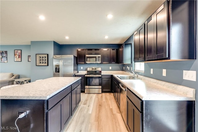 kitchen with light hardwood / wood-style floors, sink, stainless steel appliances, and a center island