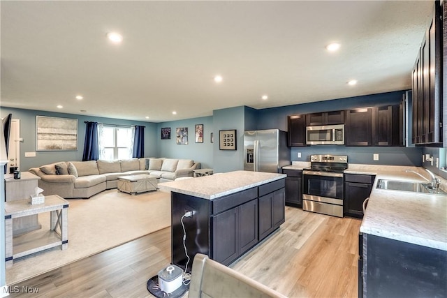 kitchen with stainless steel appliances, a center island, sink, and light wood-type flooring