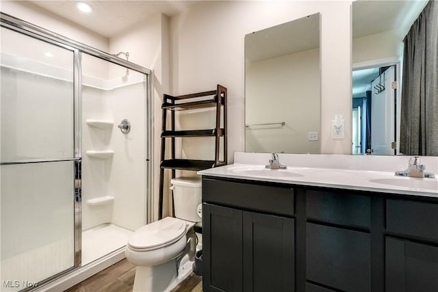 bathroom featuring vanity, toilet, a shower with shower door, and hardwood / wood-style floors