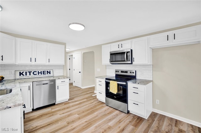 kitchen featuring white cabinetry, appliances with stainless steel finishes, decorative backsplash, and light wood-type flooring