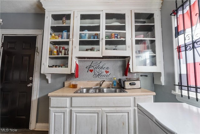 kitchen featuring sink, backsplash, and white cabinets