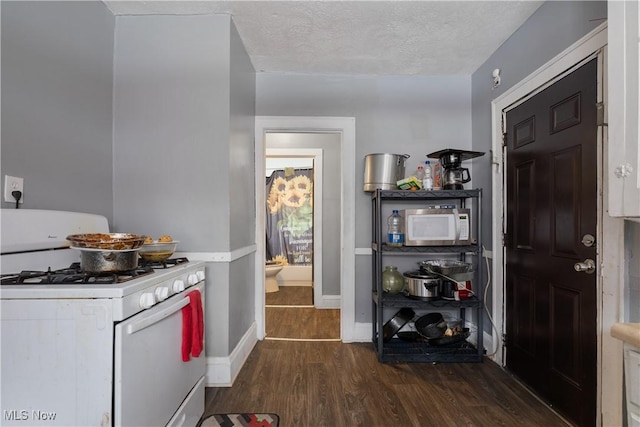 kitchen with white appliances, dark hardwood / wood-style flooring, and a textured ceiling