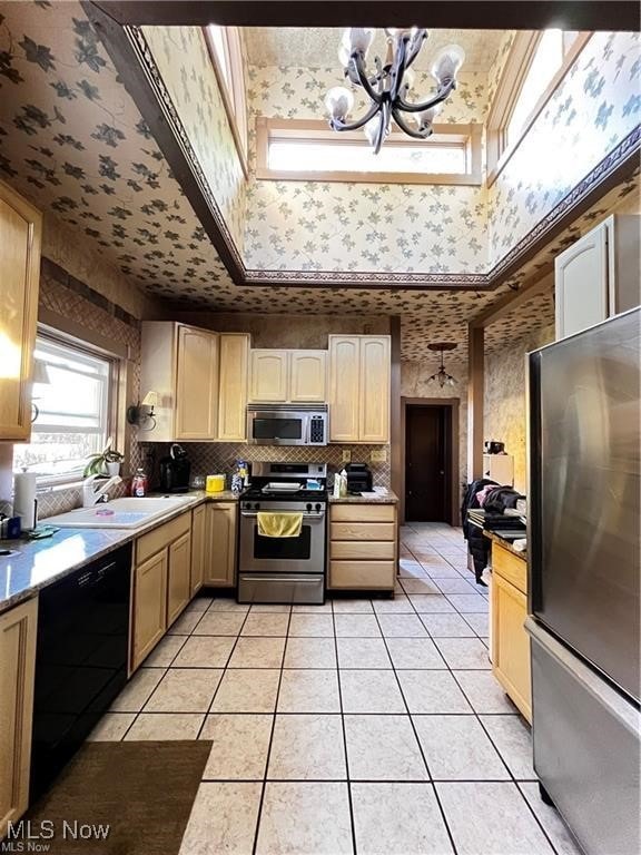 kitchen featuring light tile patterned floors, sink, stainless steel appliances, light brown cabinetry, and a chandelier