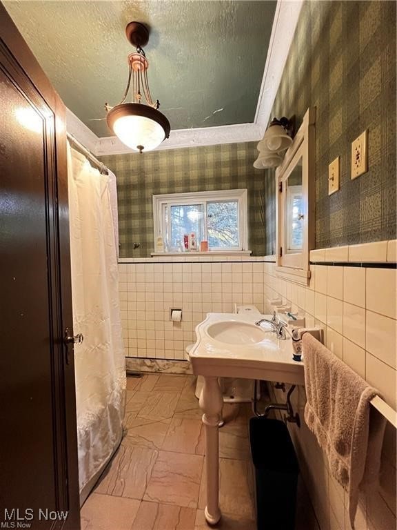 bathroom with tile walls and a textured ceiling