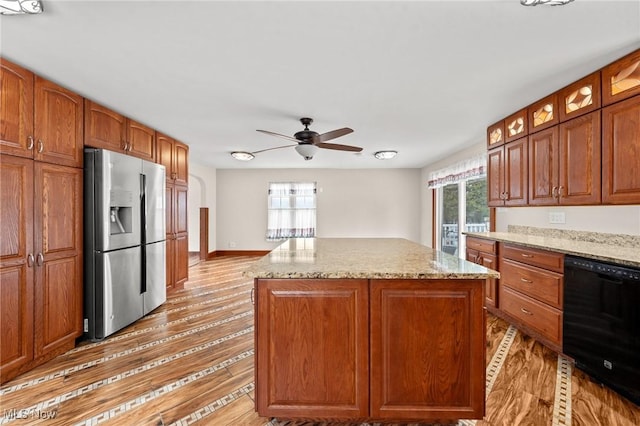 kitchen featuring a wealth of natural light, dishwasher, stainless steel fridge, a center island, and light stone countertops