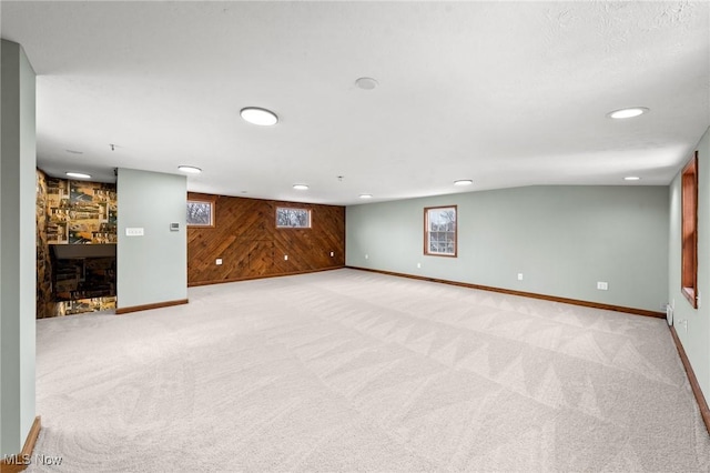 basement featuring light colored carpet and wood walls