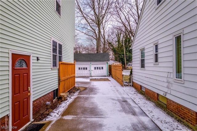 snow covered patio with a garage and an outbuilding