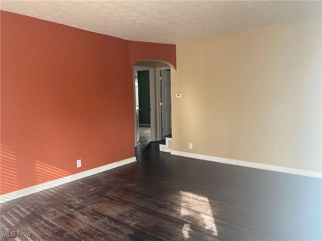 spare room featuring dark hardwood / wood-style flooring and a textured ceiling