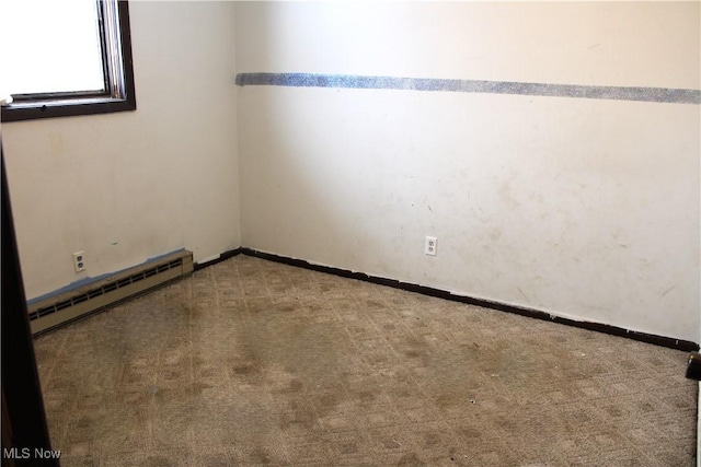 carpeted empty room with a baseboard heating unit