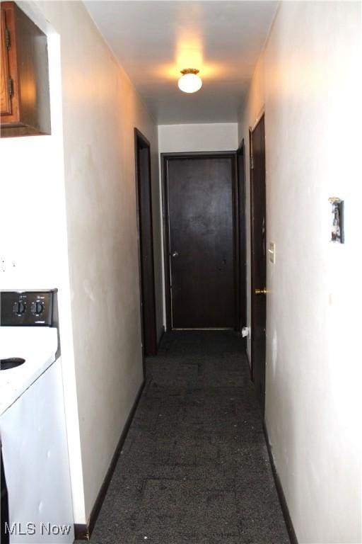 hall with washer / dryer and dark carpet