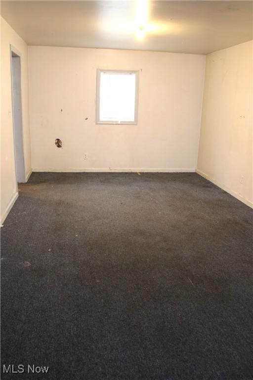 spare room with dark colored carpet