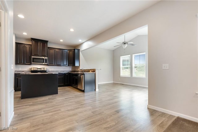 kitchen featuring vaulted ceiling, appliances with stainless steel finishes, a center island, ceiling fan, and light hardwood / wood-style flooring