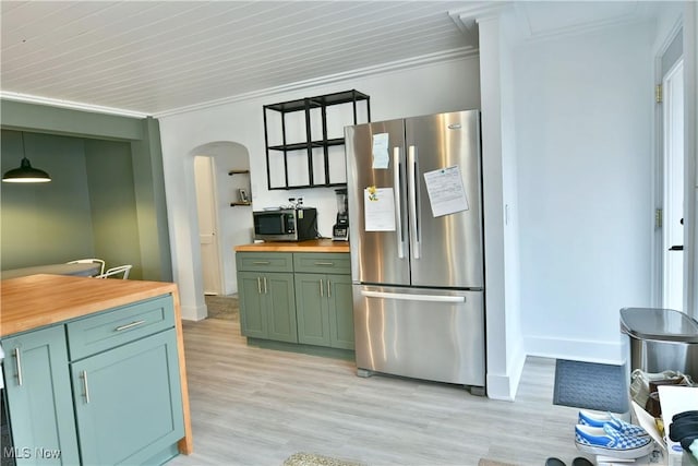 kitchen with ornamental molding, appliances with stainless steel finishes, butcher block countertops, and decorative light fixtures