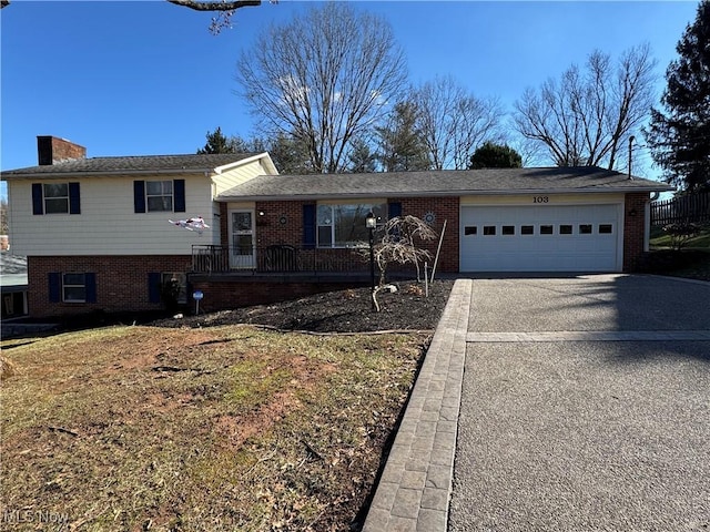 tri-level home with a garage, driveway, and brick siding