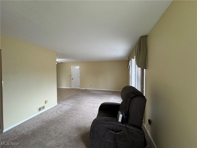 sitting room featuring visible vents, a textured ceiling, baseboards, and carpet flooring