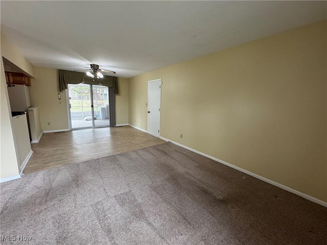 interior space with wood finished floors, a ceiling fan, and baseboards