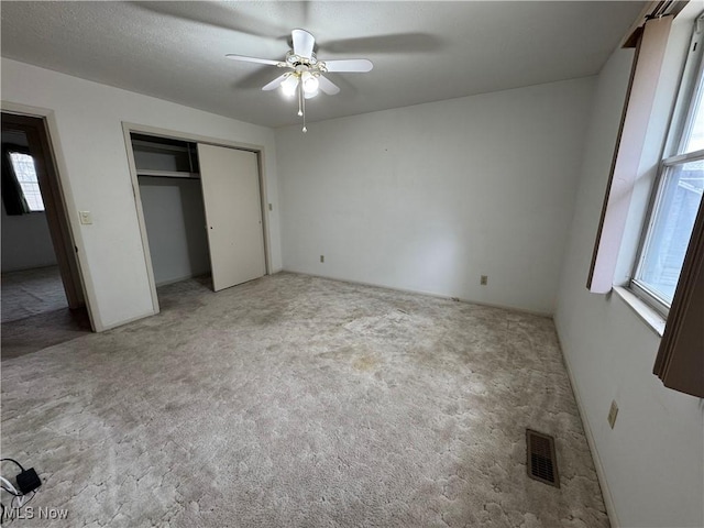 unfurnished bedroom featuring carpet floors, a closet, visible vents, and a ceiling fan