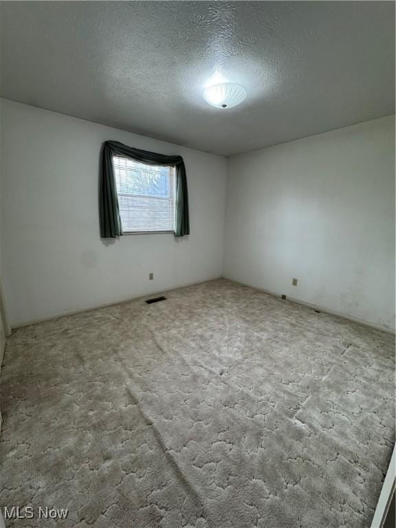 carpeted empty room featuring visible vents and a textured ceiling