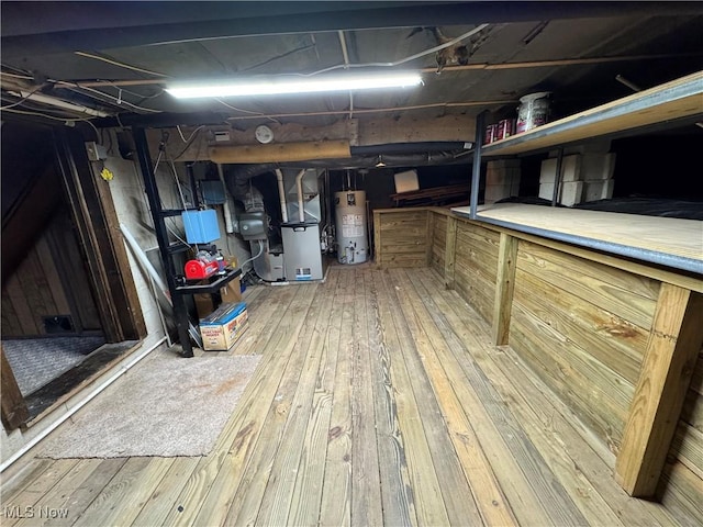 basement with heating unit, hardwood / wood-style flooring, and water heater