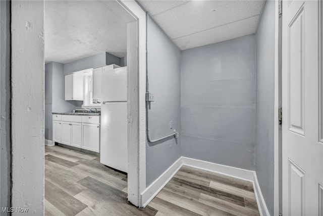 hall with a drop ceiling, sink, and light hardwood / wood-style floors