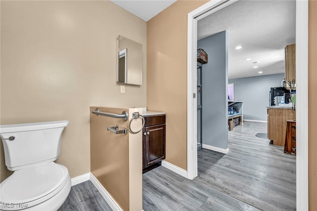 bathroom featuring vanity, wood-type flooring, and toilet