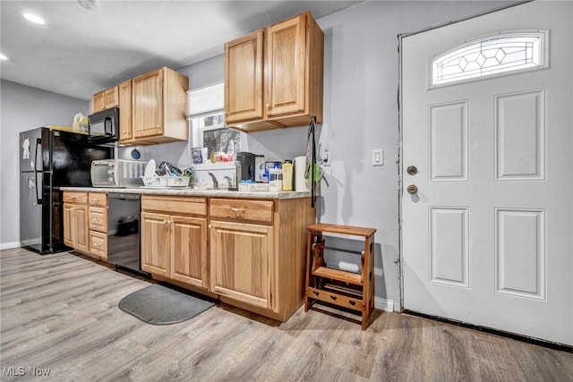 kitchen featuring plenty of natural light, light wood-type flooring, light brown cabinets, and black appliances