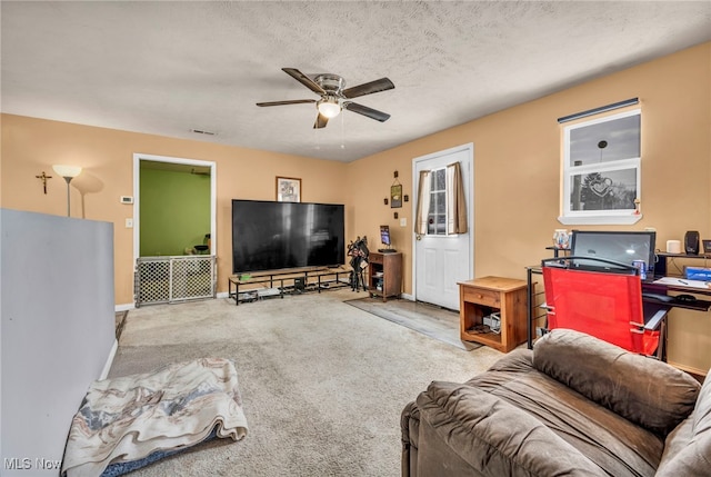 carpeted living room with ceiling fan and a textured ceiling