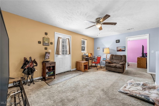 living room featuring ceiling fan, carpet floors, and a textured ceiling