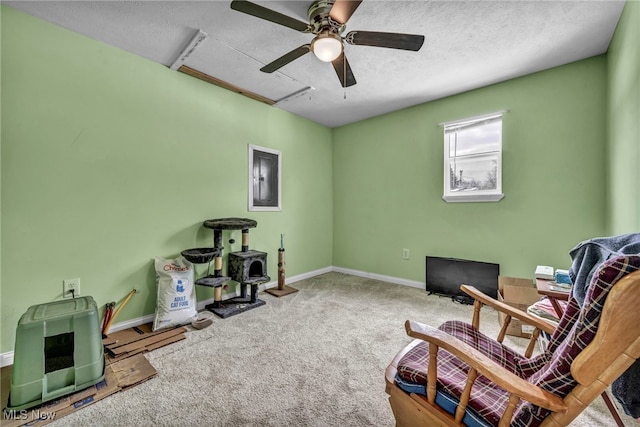 sitting room featuring ceiling fan, carpet, electric panel, and a textured ceiling