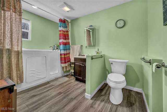 bathroom with vanity, a tub to relax in, hardwood / wood-style floors, and toilet