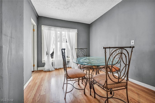 dining space featuring a textured ceiling and light wood-type flooring