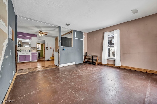 unfurnished living room with a textured ceiling, concrete flooring, and ceiling fan