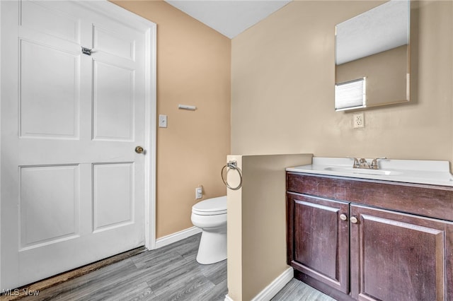 bathroom with hardwood / wood-style flooring, vanity, and toilet