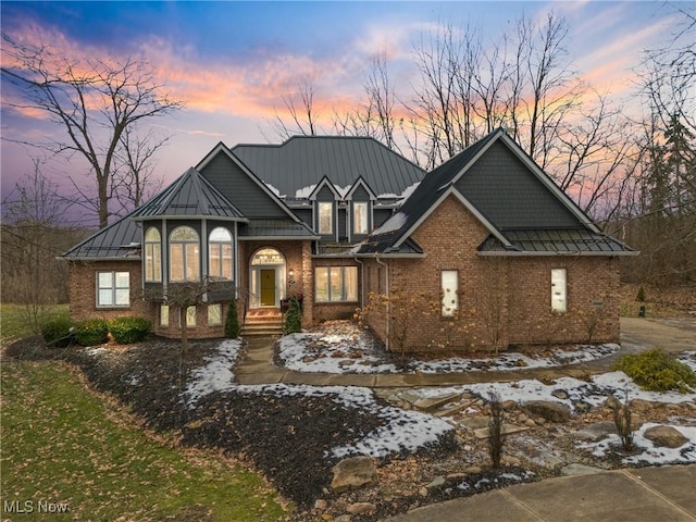 view of front of property with metal roof, brick siding, and a standing seam roof