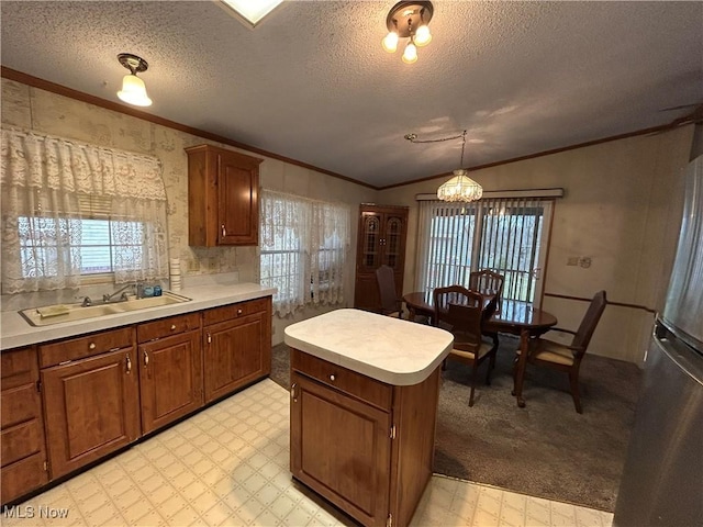 kitchen with lofted ceiling, sink, hanging light fixtures, a textured ceiling, and ornamental molding