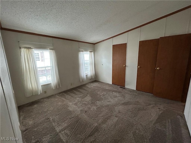 unfurnished bedroom with crown molding, dark carpet, and a textured ceiling