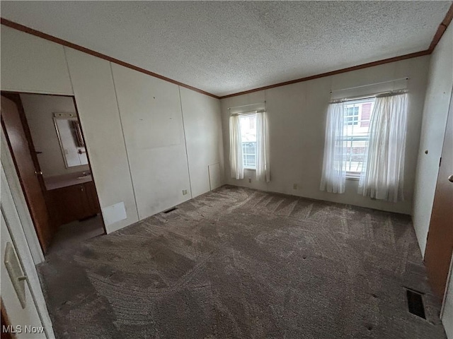 unfurnished bedroom featuring ornamental molding, a textured ceiling, and dark carpet