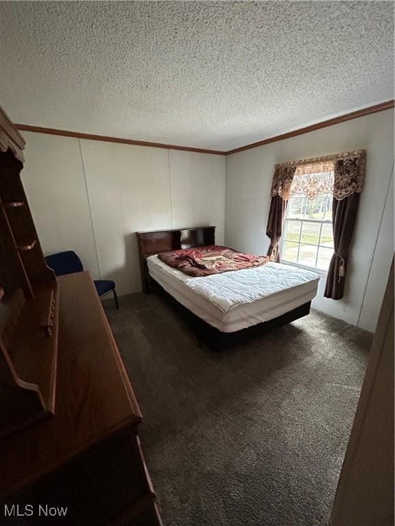 bedroom with ornamental molding, a textured ceiling, and dark colored carpet