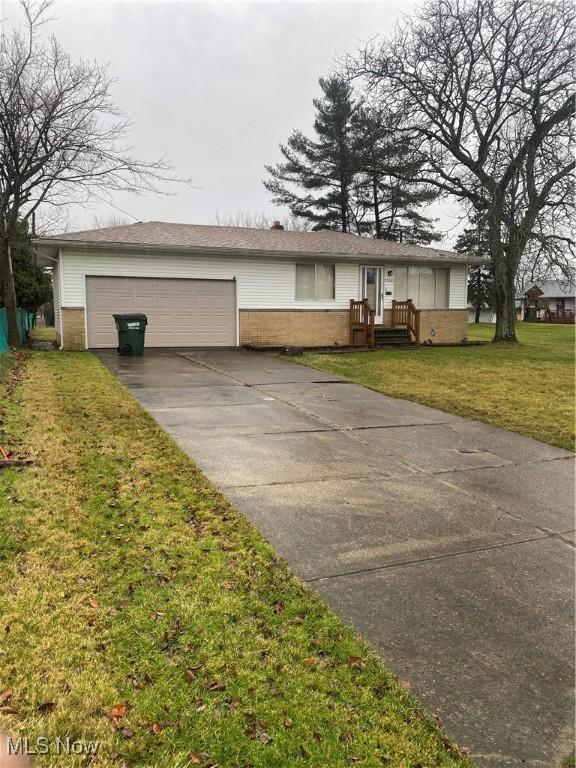 ranch-style home with a garage and a front lawn